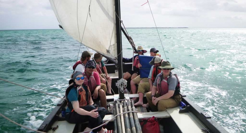 a group of veterans sit on a sailboat on an outward bound expedition 